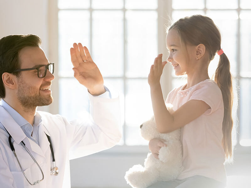 young girl smiling with doctor giving high five
