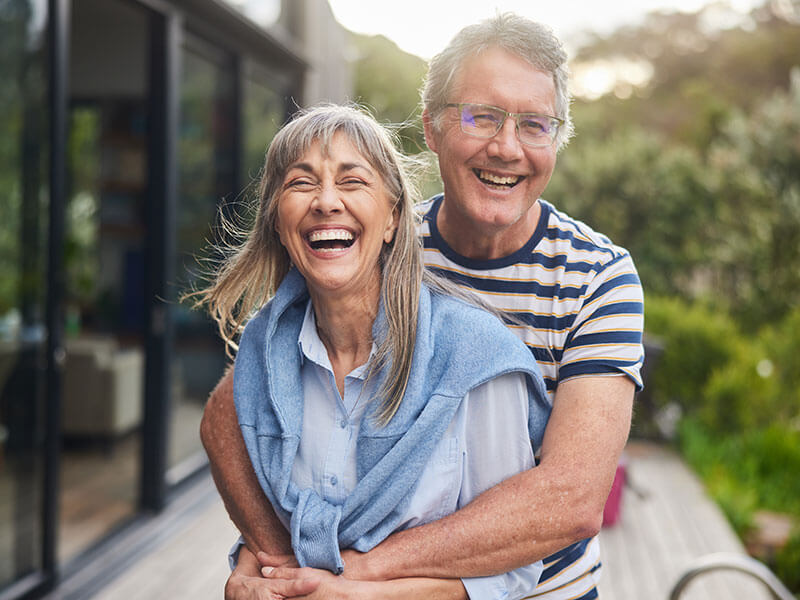 man and woman smiling together outside home