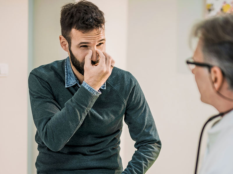 man holding face in pain while in exam with doctor