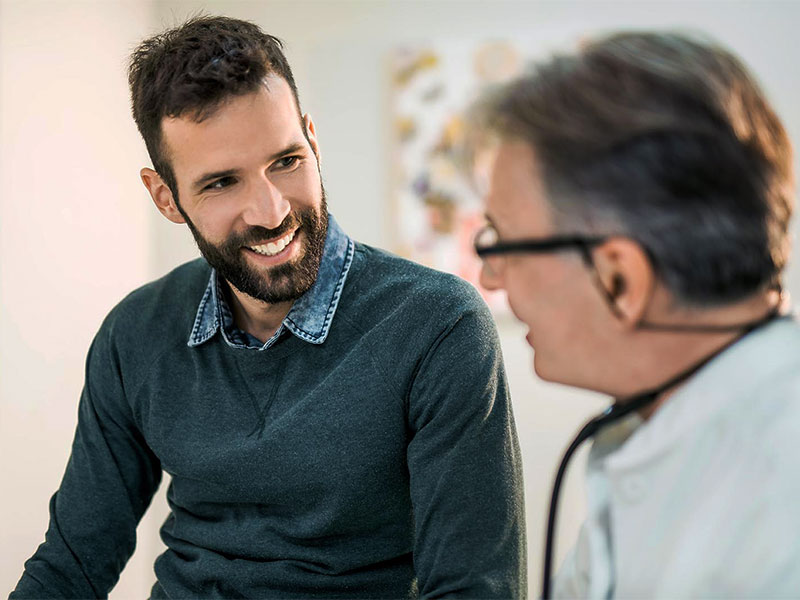 man smiling while being examined by doctor